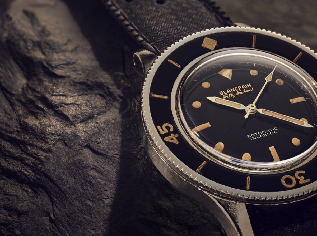 Blancpain Fifty-Fathoms sur un rocher sombre, cadran noir et index dorés